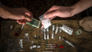 A man holds a bag filled with money and drugs