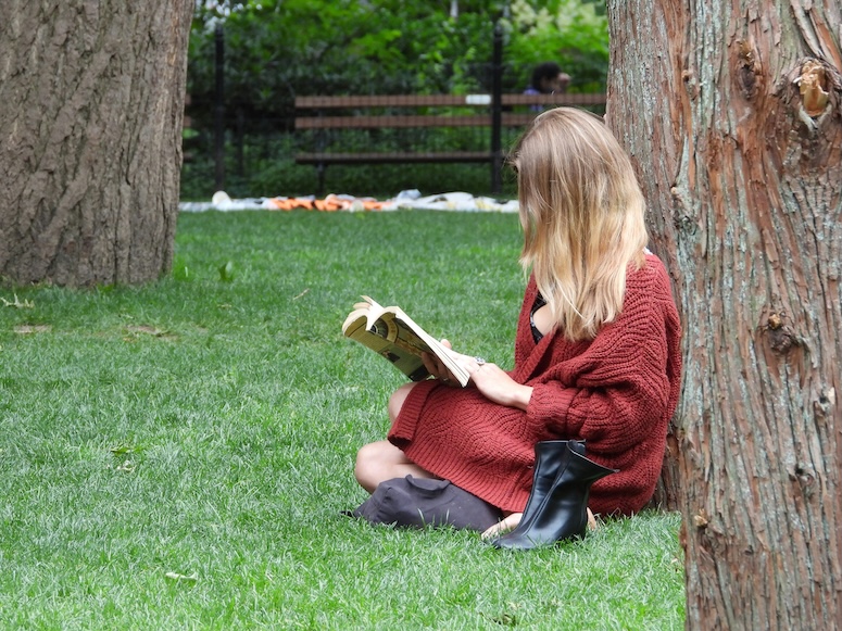Woman sitting on grass reading a book in a park, symbolizing clear Colorado criminal law guides and resources.
