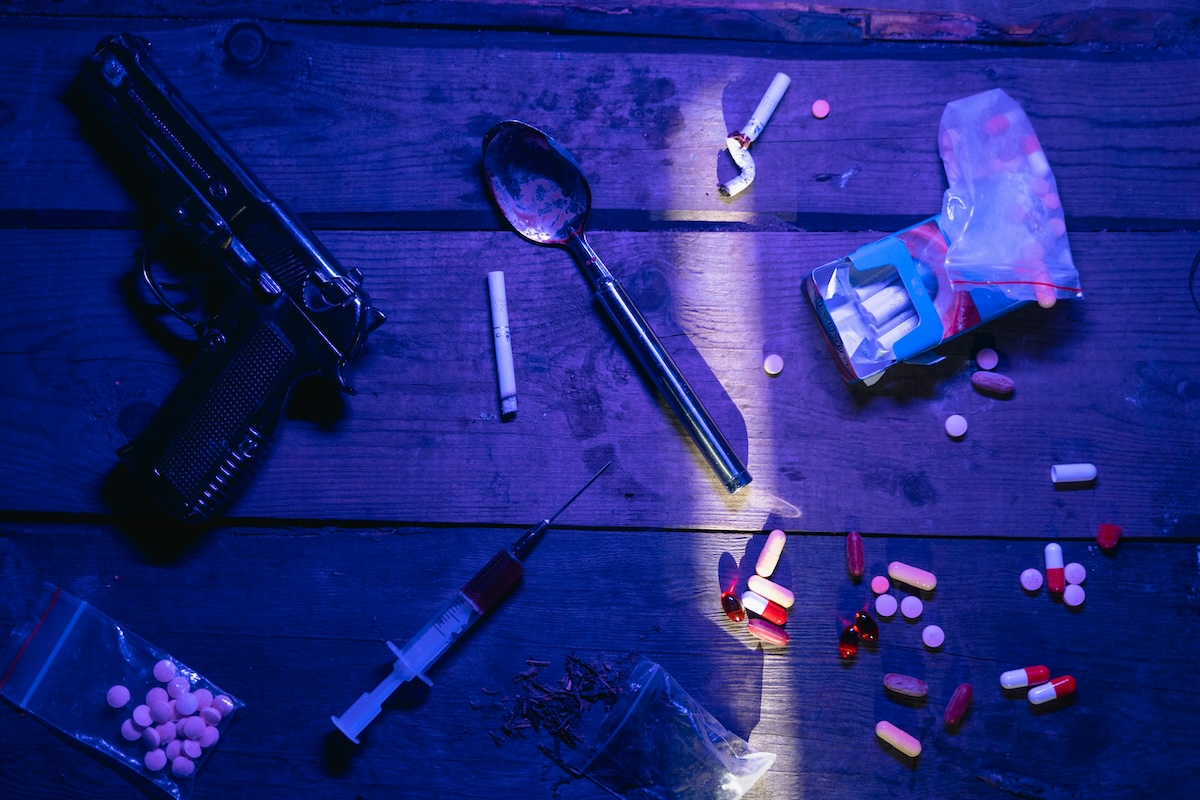 Drugs and paraphernalia on a table under blue light, symbolizing Colorado drug crime defense.