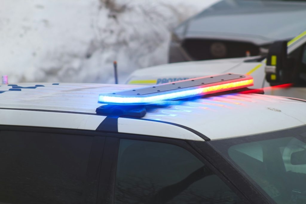 Colorado police cruiser with flashing red and blue lights during a traffic stop — representing speeding and moving violation enforcement.