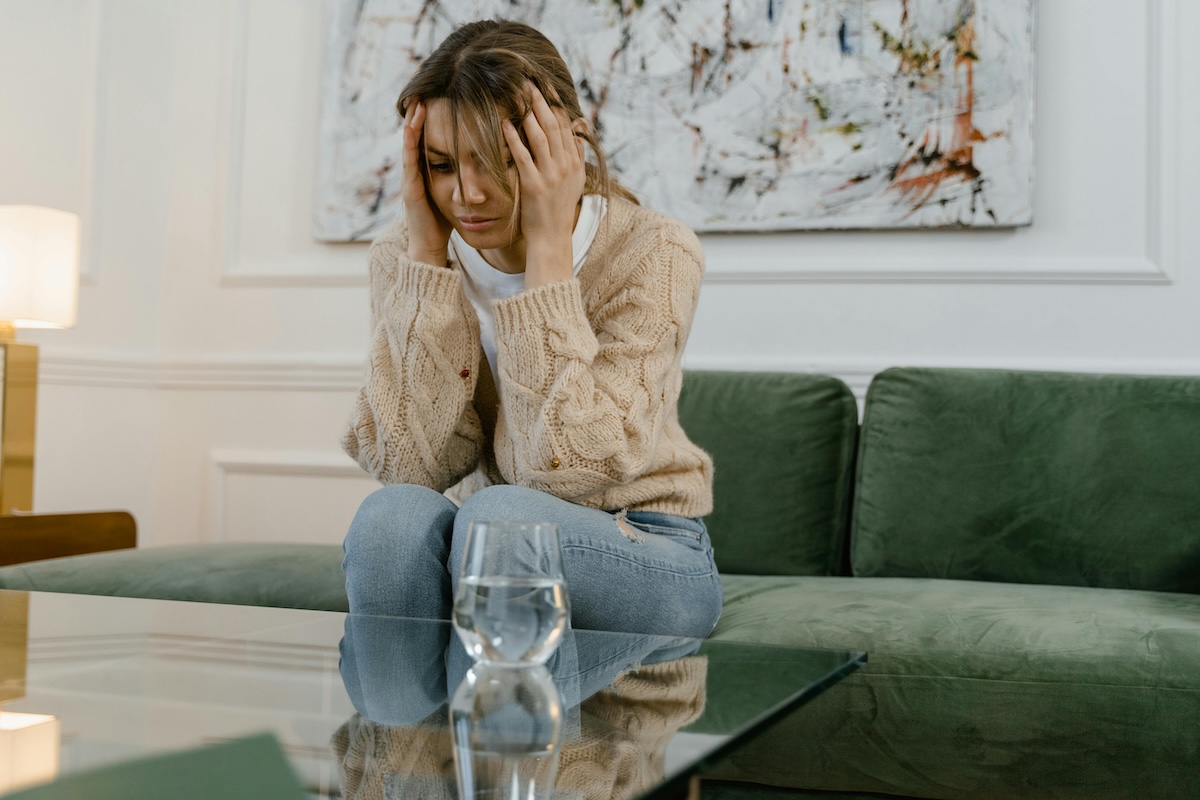 Worried woman sitting on a couch, reflecting during a difficult time, symbolizing domestic violence defense and support.
