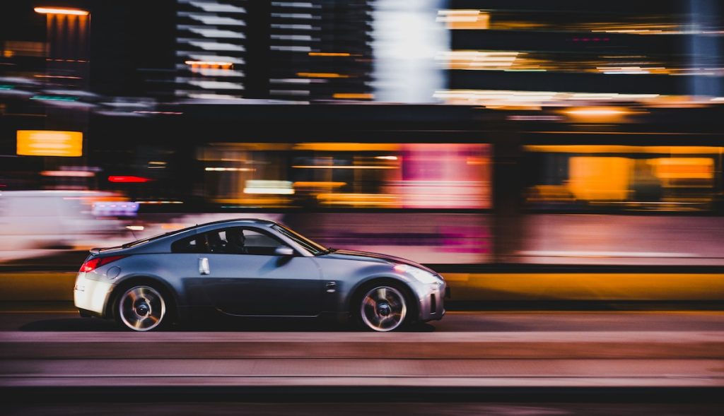 Silver sports car speeding through city lights at night — symbolizing the speed and urgency of reckless driving cases in Colorado.
