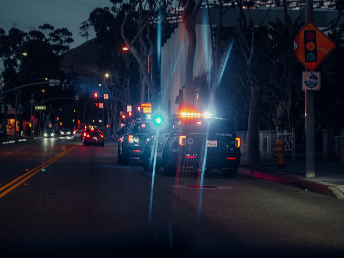 Police vehicles with flashing lights during a nighttime traffic stop on a city street.