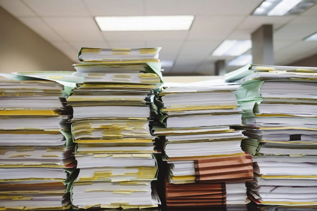 Stacks of thick case files with yellow tabs in an office