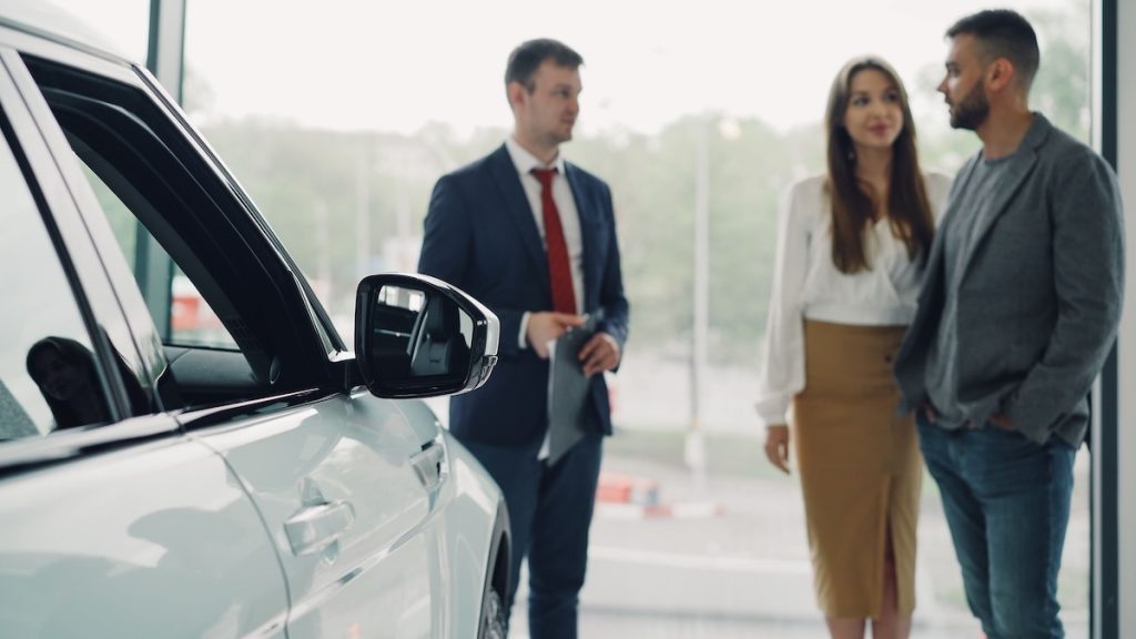 Motor vehicle salesperson assisting customers at a car dealership